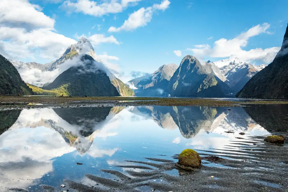 Milford Sound refletido na água, com montanhas ao redor
